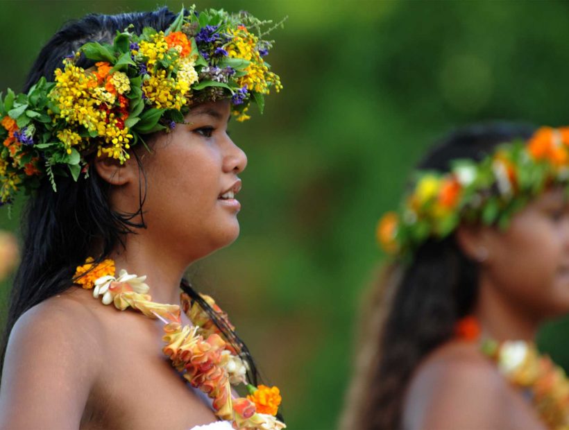 Polynesische Tänzerinnen mit bunten Blumenkränzen bei einer traditionellen Tanzvorführung.
